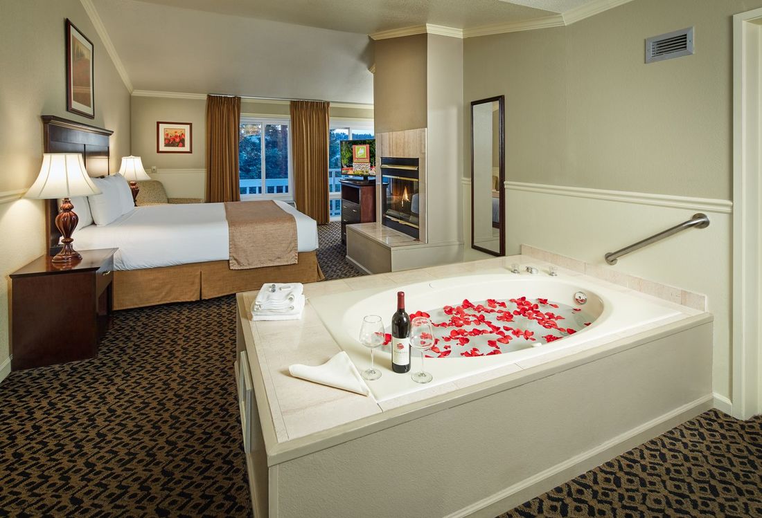 King bed guest room with fire place and rose petals in whirlpool tub